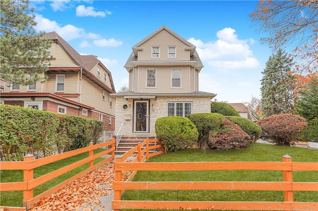 view of front facade featuring stone siding, a fenced front yard, and a front lawn