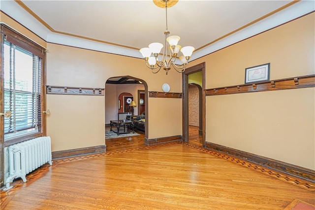 33 Wellington Ct, Brooklyn, NY 11230 - empty room featuring radiator heating unit, arched walkways, a chandelier, light wood finished floors, and healthy amount of natural light