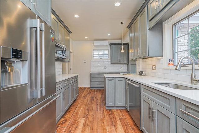 33 Wellington Ct, Brooklyn, NY 11230 - kitchen with stainless steel appliances, a sink, a wall mounted AC, wood finished floors, and gray cabinetry