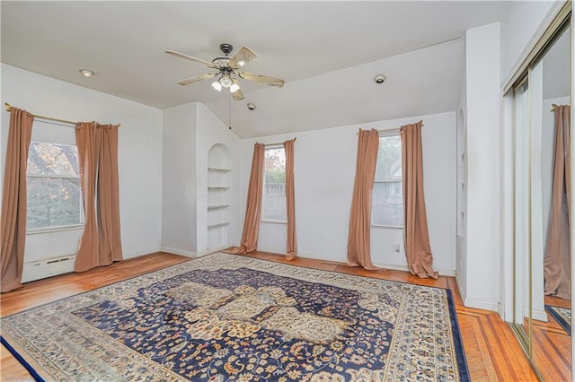 unfurnished room with a baseboard heating unit, lofted ceiling, ceiling fan, and wood finished floors