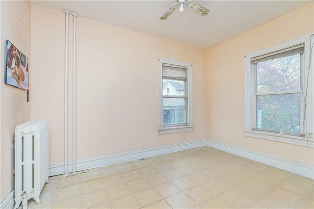 unfurnished room with radiator heating unit, a healthy amount of sunlight, baseboards, and ceiling fan