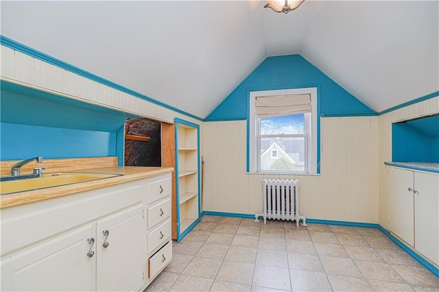 additional living space with radiator heating unit, lofted ceiling, and a sink