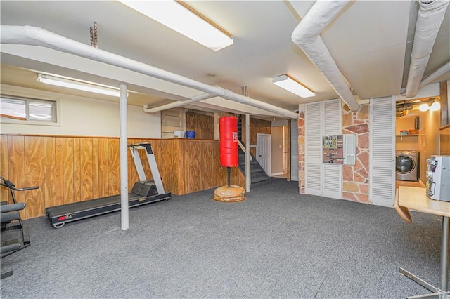 workout room featuring washer / dryer, wooden walls, carpet flooring, and a wainscoted wall