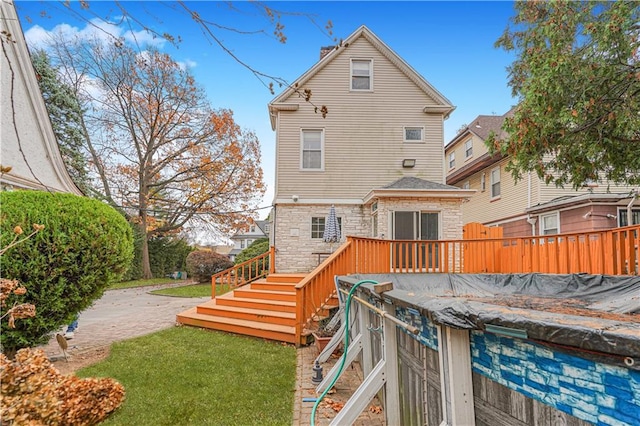 rear view of property featuring a chimney, stone siding, a deck, and stairs