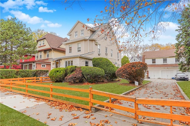 view of front of home featuring a fenced front yard, a front yard, stone siding, and a garage