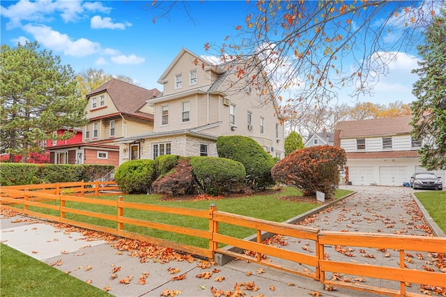 view of front of house featuring fence, an attached garage, and a front lawn