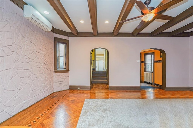 unfurnished room featuring arched walkways, beamed ceiling, a wall mounted AC, and baseboards