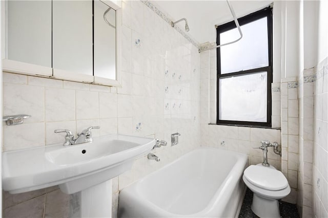 bathroom with tiled shower / bath combo, toilet, and tile walls