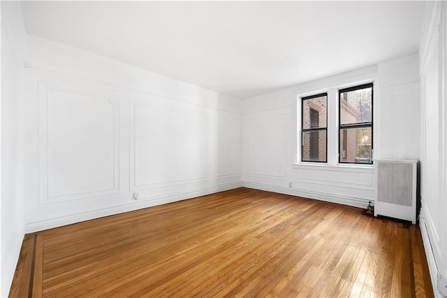 unfurnished room with radiator and hardwood / wood-style floors