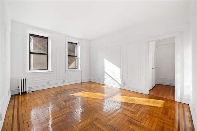 empty room featuring radiator heating unit and parquet floors