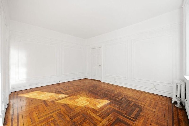 empty room featuring radiator heating unit and parquet floors