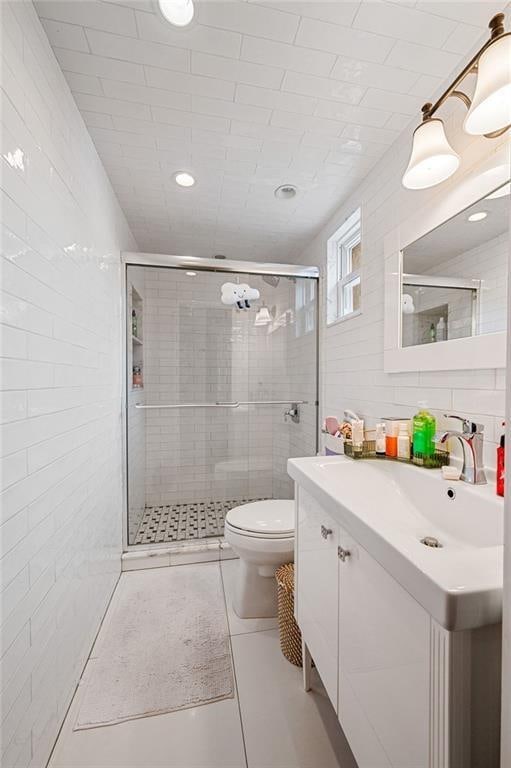 bathroom featuring toilet, a shower stall, tile walls, and vanity