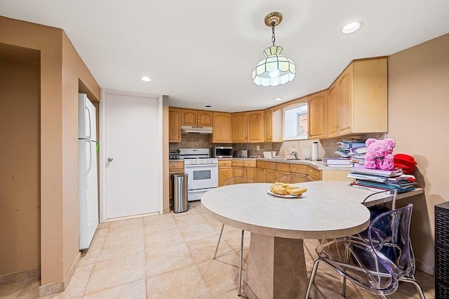 kitchen with white appliances, decorative backsplash, hanging light fixtures, light countertops, and under cabinet range hood