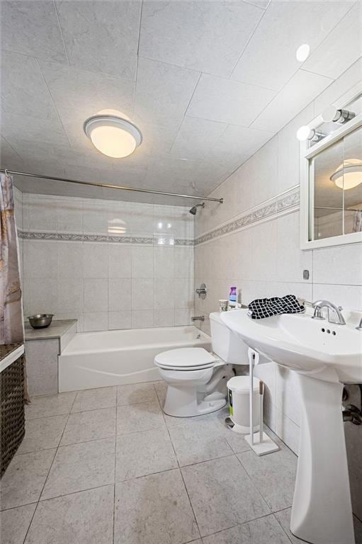 full bathroom featuring toilet, tile patterned floors, tile walls, and shower / bathtub combination with curtain