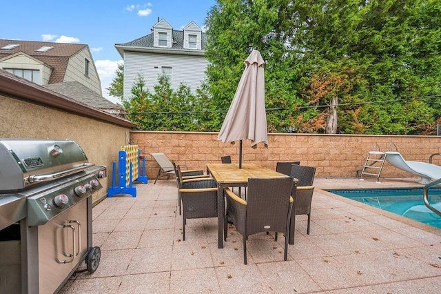 view of patio featuring outdoor dining area, area for grilling, fence, and a fenced in pool