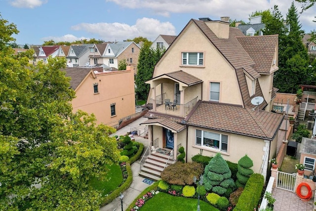 view of front of property with a tiled roof, a chimney, a residential view, and stucco siding