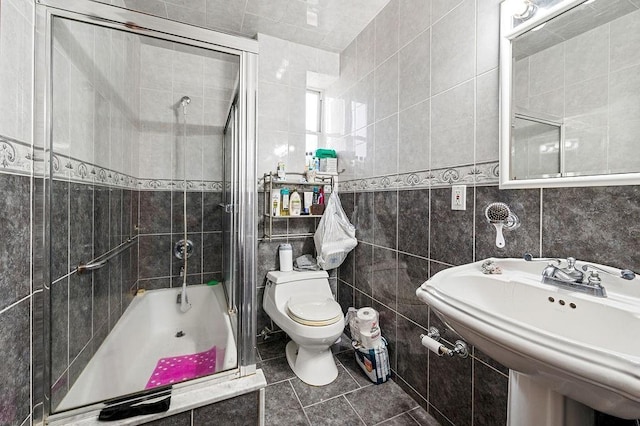 bathroom with toilet, tiled shower / bath combo, a sink, and tile walls