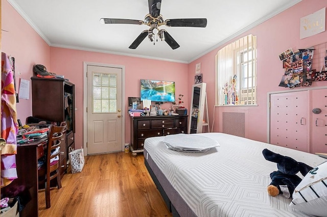 bedroom featuring light wood-style flooring, multiple windows, a ceiling fan, and crown molding