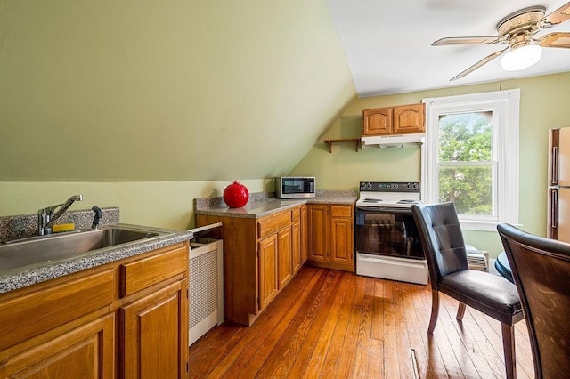 kitchen with brown cabinets, electric stove, stainless steel microwave, and dark wood finished floors