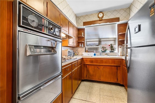 kitchen featuring brown cabinets, appliances with stainless steel finishes, light countertops, and open shelves