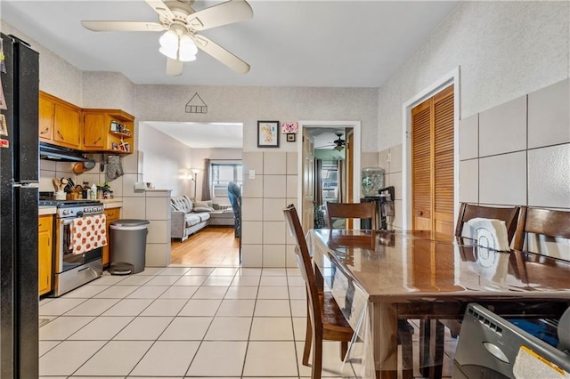 kitchen featuring a ceiling fan, open shelves, stainless steel gas stove, under cabinet range hood, and light tile patterned flooring