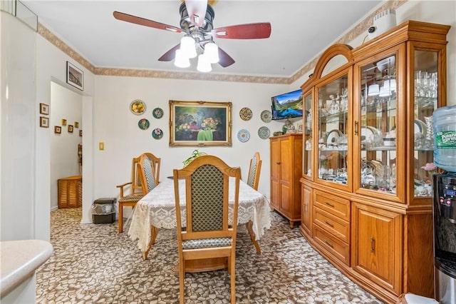 carpeted dining space with crown molding and ceiling fan