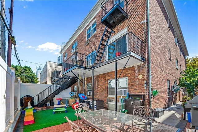rear view of property featuring stairs, outdoor dining space, brick siding, and a patio