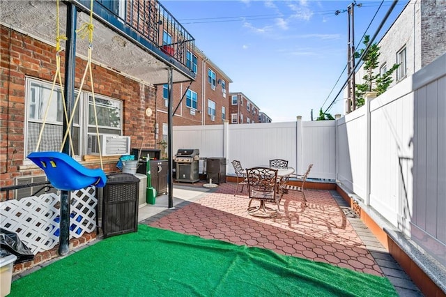 view of patio / terrace featuring a grill, cooling unit, outdoor dining space, and a fenced backyard