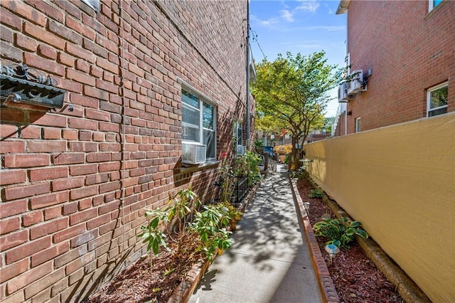 view of side of property featuring cooling unit, brick siding, and fence