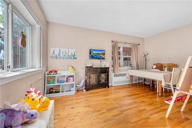 recreation room featuring radiator and wood finished floors