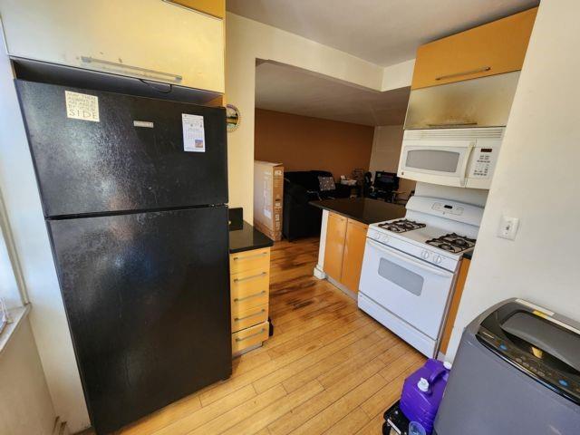 kitchen with white appliances and light hardwood / wood-style floors