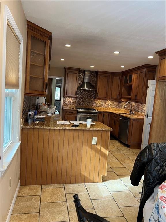 kitchen with black dishwasher, stainless steel gas range, wall chimney exhaust hood, and kitchen peninsula