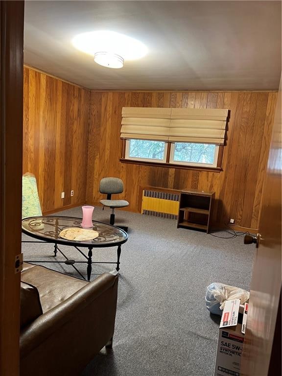 living area featuring carpet flooring, radiator heating unit, and wooden walls