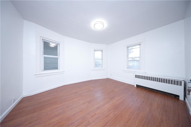 spare room with radiator heating unit, baseboards, and dark wood finished floors