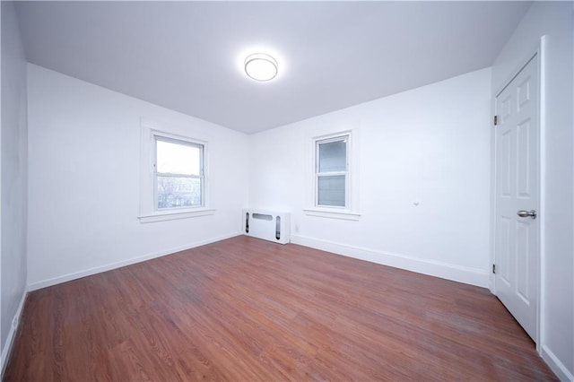 spare room with heating unit, dark wood finished floors, and baseboards