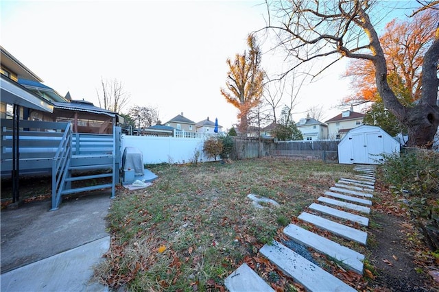 view of yard featuring an outbuilding, a fenced backyard, and a storage shed