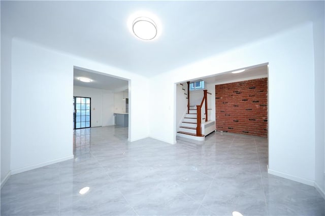 empty room featuring baseboards and stairway