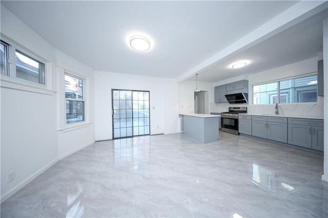 kitchen with stainless steel gas range, gray cabinets, light countertops, and marble finish floor