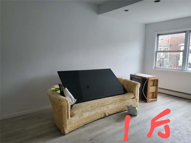 sitting room featuring hardwood / wood-style floors, beamed ceiling, and a baseboard heating unit