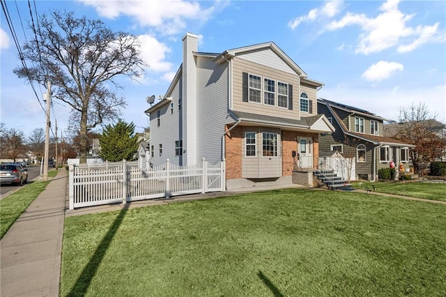 rear view of property with a chimney, fence, a lawn, and brick siding