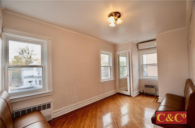 interior space with an AC wall unit, radiator, crown molding, and light hardwood / wood-style floors