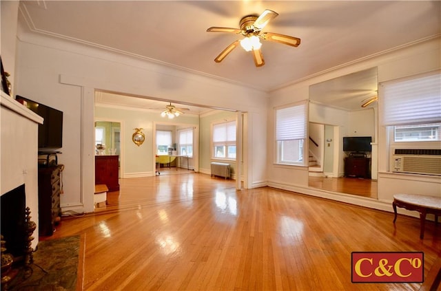 unfurnished living room featuring cooling unit, ceiling fan, crown molding, light hardwood / wood-style flooring, and radiator heating unit