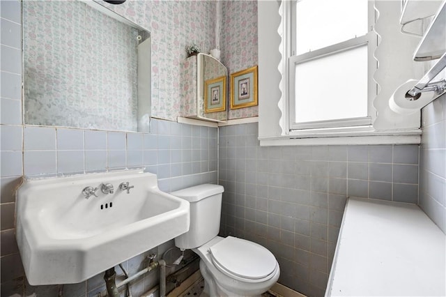 bathroom featuring sink, tile walls, and toilet