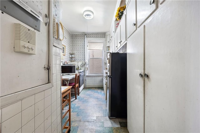 kitchen with white cabinetry, tile walls, and stainless steel refrigerator