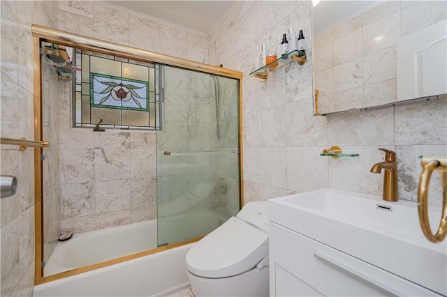 full bathroom featuring toilet, tile walls, crown molding, bath / shower combo with glass door, and vanity