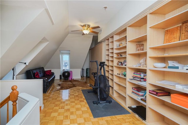 exercise room featuring ceiling fan, light parquet flooring, and lofted ceiling