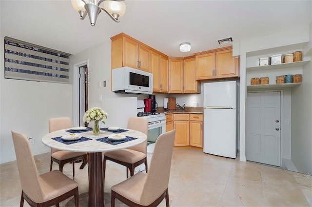 kitchen with white appliances, light brown cabinets, and a chandelier