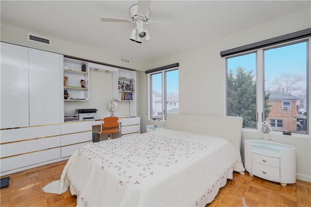 bedroom with light parquet floors, multiple windows, and ceiling fan