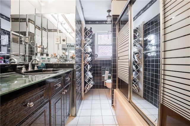 full bathroom with toilet, combined bath / shower with glass door, tile walls, vanity, and tile patterned flooring