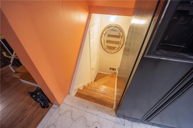 staircase featuring wood finished floors and visible vents